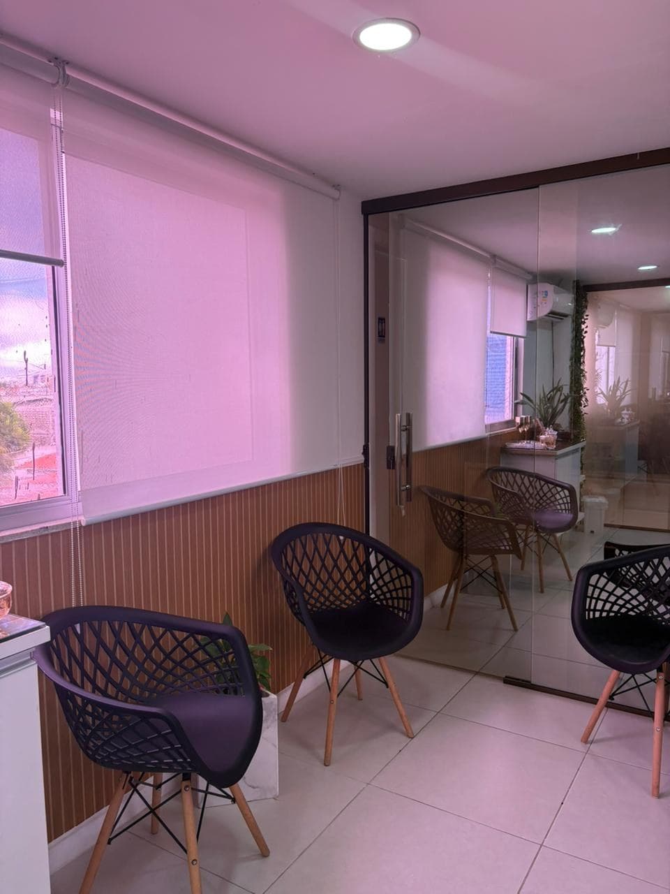 Sala de espera da Clínica Âme com poltronas e luz rosada.